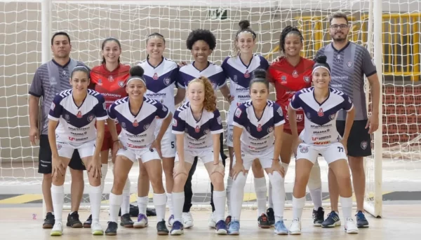 Equipe de jogadoras e comissão técnica do Cianorte Futsal Feminino posando para foto oficial dentro da quadra do ginásio