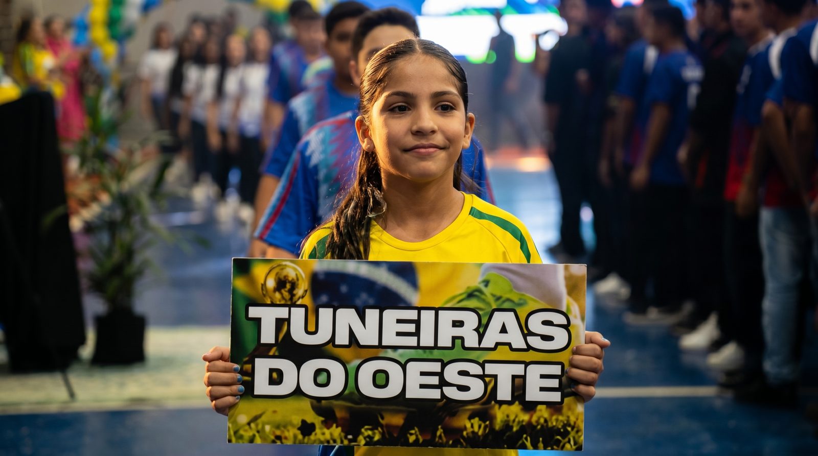 Aluna atleta segura a placa do município na cerimônia de abertura dos Jogos Escolares em Tuneiras do Oeste