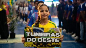 Aluna atleta segura a placa do município na cerimônia de abertura dos Jogos Escolares em Tuneiras do Oeste
