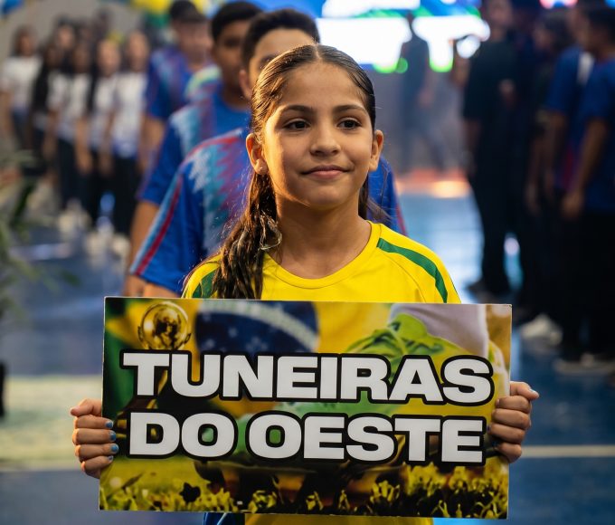Aluna atleta segura a placa do município na cerimônia de abertura dos Jogos Escolares em Tuneiras do Oeste